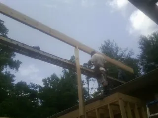 Carpenter setting a ridge beam over a new addition frame — Ice Dam Removal by Roofing Brothers in Thurston