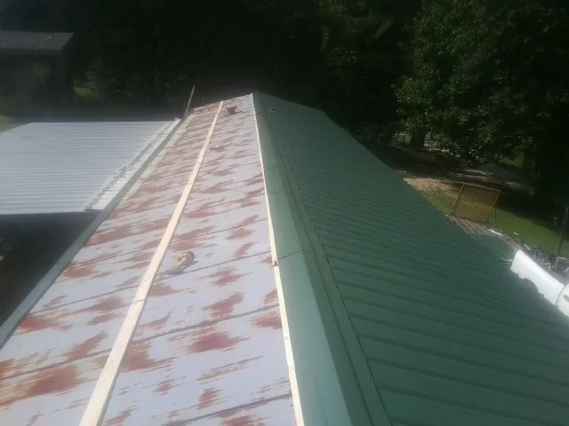 Old rusted panels beside newly installed green metal roofing — Wind Damage Roof Repair by Roofing Brothers in Thurston