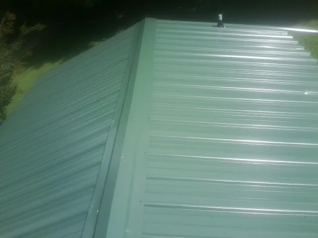 New green metal panels meeting at the ridge of a roof — Flat Roof Repair work by our crew in Thurston
