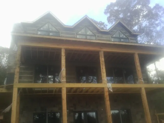 Dormers and porch framing on a large log home under construction — Roof Coating work by our crew in Thurston
