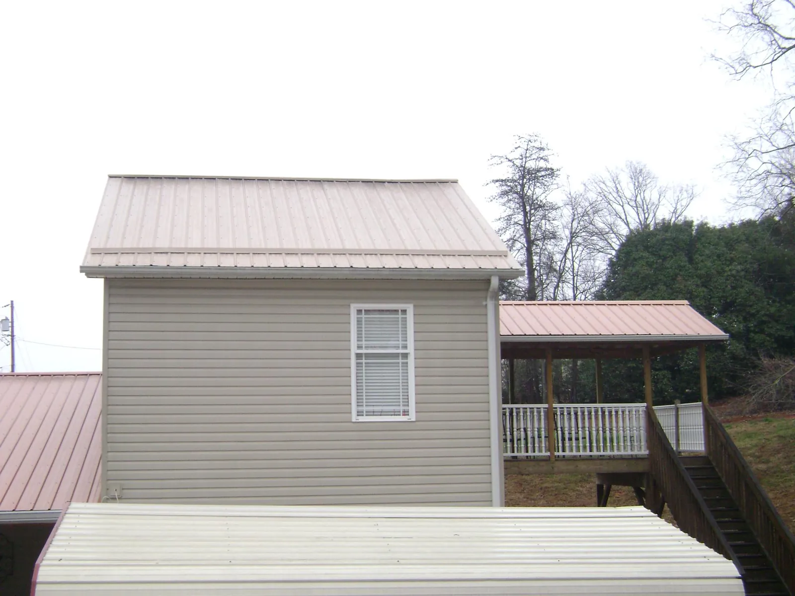Tan metal roofs on a two story addition and attached porch, from a Roof Replacement job in Thurston