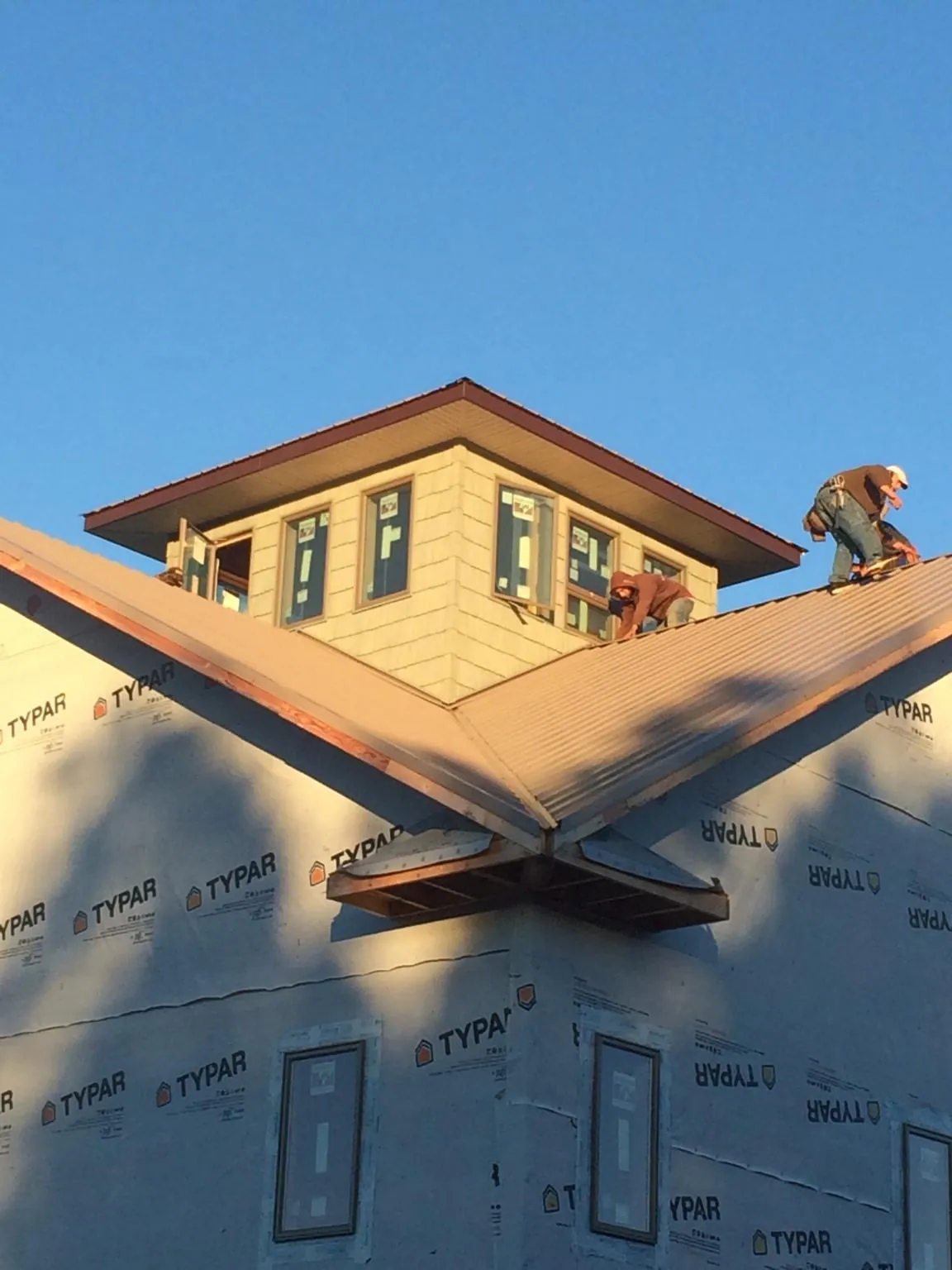 Roofers working around a rooftop cupola on a new metal roof at sunset — Roof Waterproofing in Thurston by Roofing Brothers
